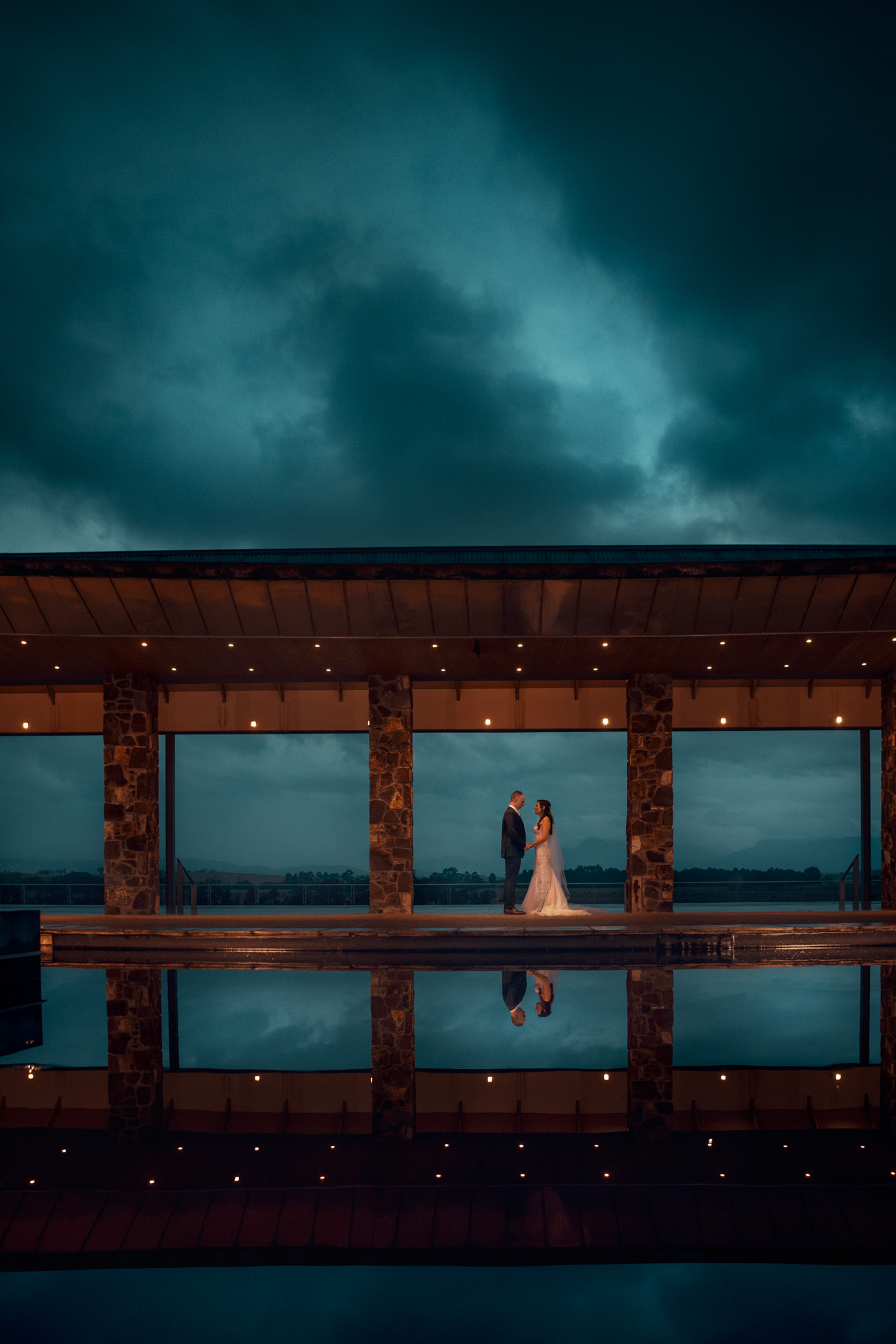 Couple stand in open passageway with dark moody blue sky above on wedding day at Yering Station Winery