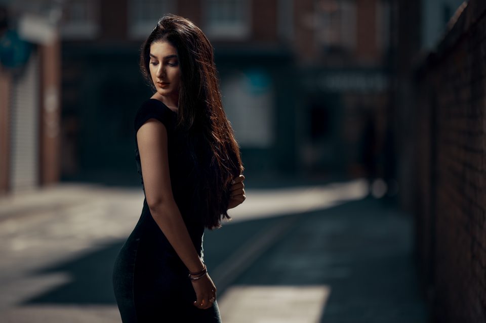 Female looking over shoulder dressed in black in laneway in london
