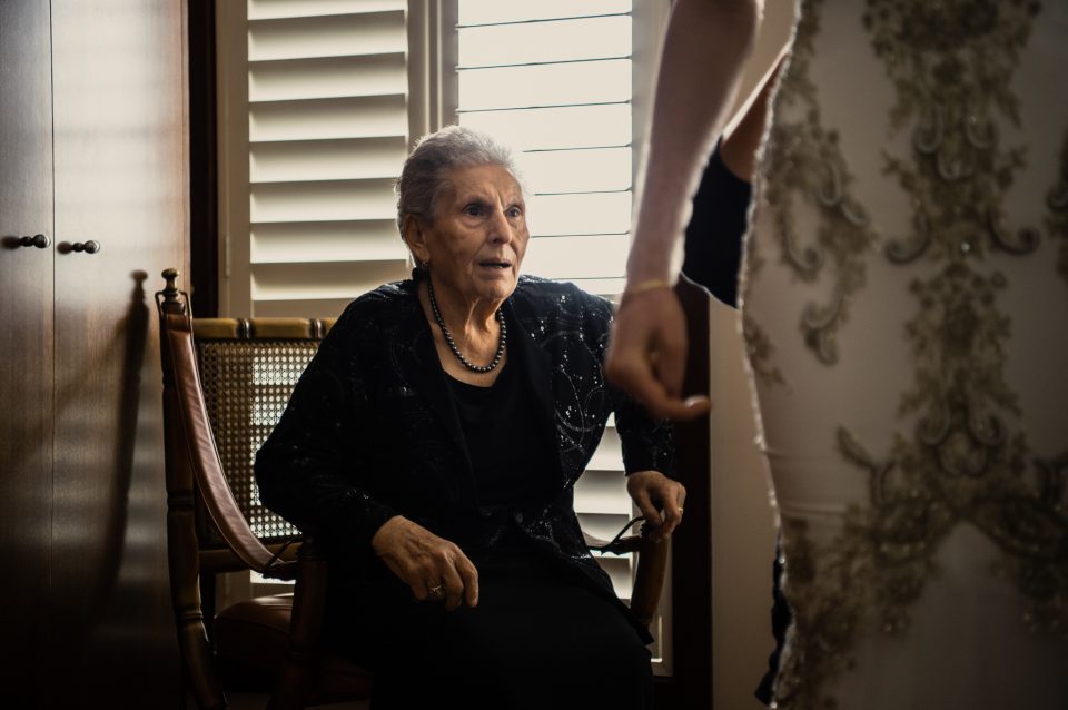 Candid wedding photo of grandma seated looking at bride getting ready