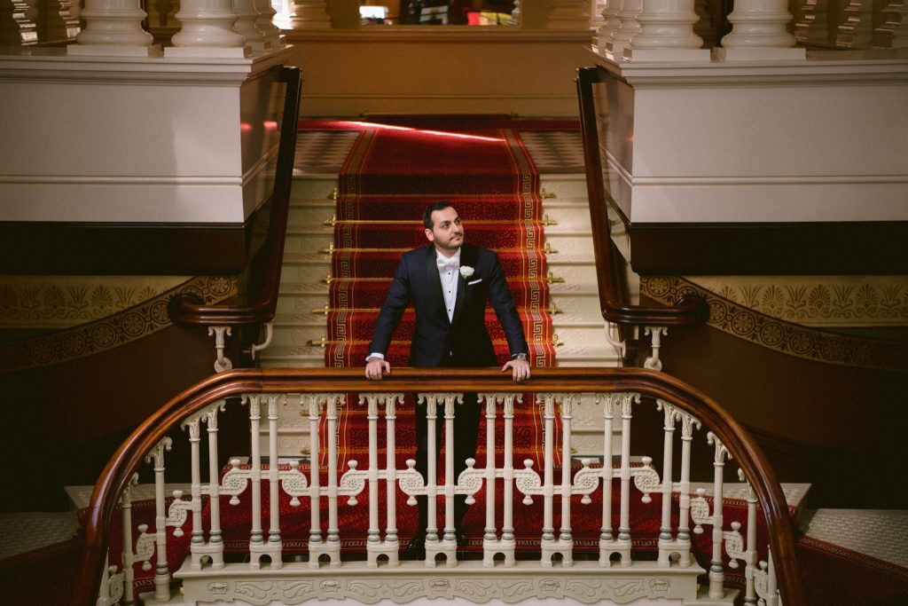 groom waiting for the first look of his bride on grand stair case