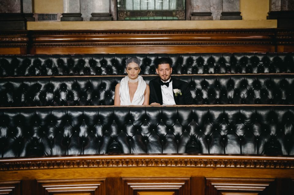 Wedding couple sit on the black leather seats in the chambers of the Melbourne town hall