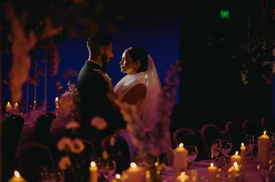 Couple look at each other through the foreground of candles and table decorations at their wedding reception at Melbourne town hall