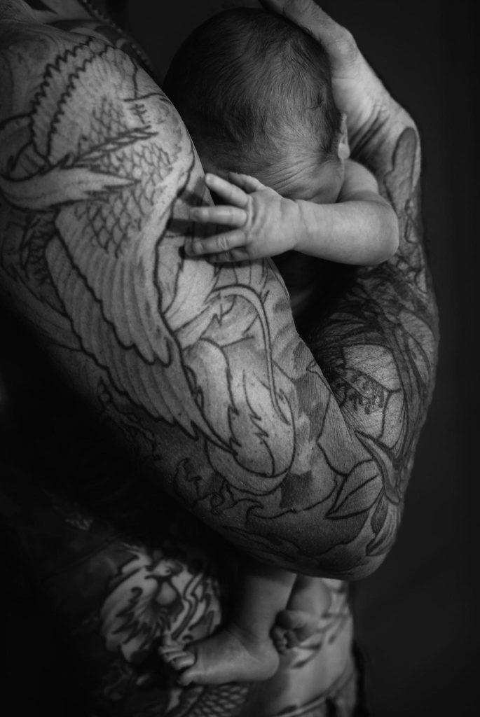 black and white photo of new born baby in fathers arms