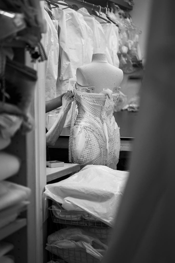 Pearls pinned onto a couture bridal gown shaped to the bride's measurements on a dress form