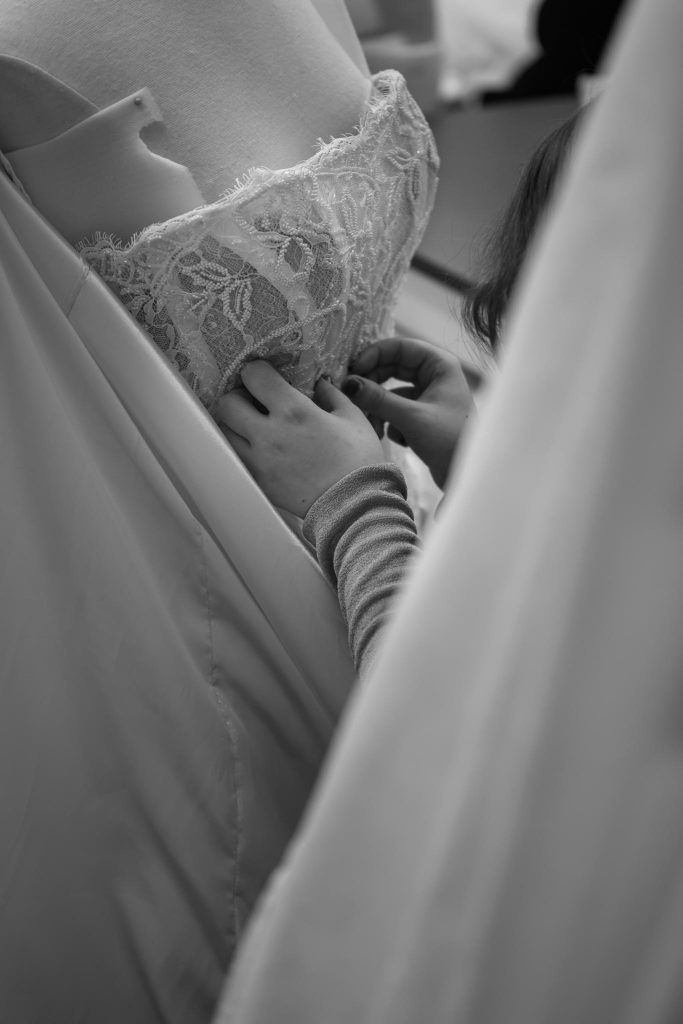 Close-up of hands sewing intricate beadwork onto a couture wedding gown